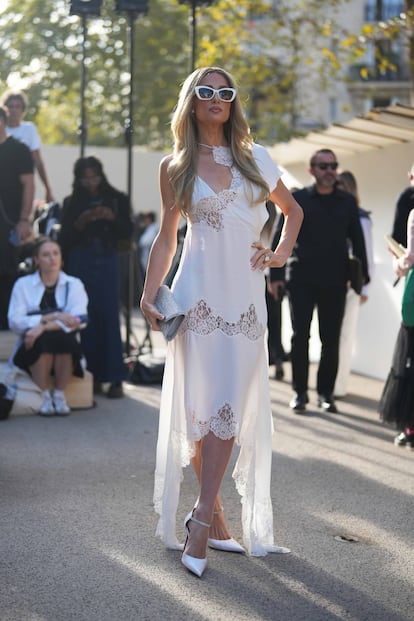 Para el desfile de Stella McCartney, Paris Hilton eligió un vestido de aires lenceros, en satén blanco y con encajes de la firma de McCartney. Lo combinó con unos zapatos de salón a juego, con una tira de pedrería que decoraba su empeine y una cartera de mano de cristales. Las gafas de sol blancas, terminaban de darle ese punto de celebrity imprescindible.