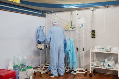 Um profissional de saúde usa o que eles chamam de capote azul, um macacão que redobra a proteção de profissionais que precisam atuar na ala de terapia intensiva, onde o risco de contágio é maior por conta dos aerossóis e respiradores utilizados pelos pacientes mais graves, que lançam gotículas no ar enquanto respiram.