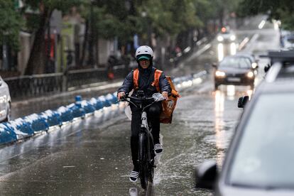 Un repartidor trabaja bajo la tormenta, este domingo en Madrid.