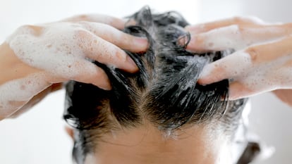 Una persona echándose champú en el cabello
