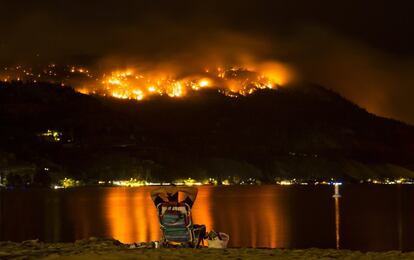 Un hombre observa un incendio forestal en el área de esquí Christie Mountain, frente al lago Skaha, en Penticton, Columbia Británica (Canadá).
