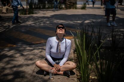 Una mujer observa el eclipse desde la avenida Paseo de la Reforma, en Ciudad de México.

