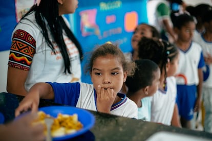 Los niños de una escuela local hacen fila para que les den un plato de comida a la hora del almuerzo.