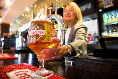Una camarera de un pub inglés sirve una cerveza Cruzcampo.