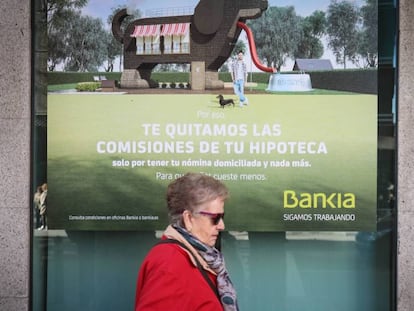 Una mujer pasa ante cartel que publicita hipotecas en una sucursal bancaria.