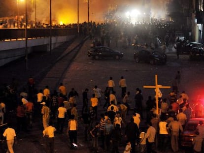 Cristianos coptos (abajo) se enfrentan a fuerzas de seguridad egipcias (arriba) mientras una multitud corre en un puente durante protestas llevadas a cabo frente al edificio de la radiotelevisión en El Cairo.