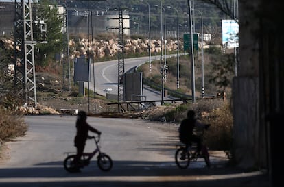 Two children look out over the road leading to the Israeli settlement of Ateret, where Palestinians are prohibited from traveling, in December 2023.