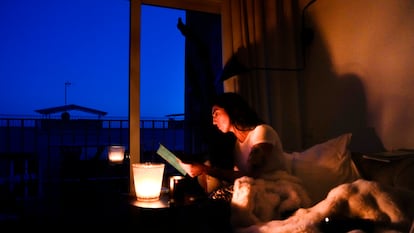 Una mujer lee en su casa con ayuda de una vela durante el apagón del lunes 29 de abril, en El Masnou (Barcelona).