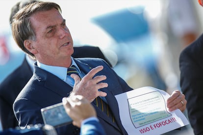 O presidente Jair Bolsonaro segura um papel com captura de tela de WhatsApp, no dia 4 de maio.