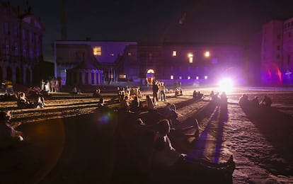 Unos peregrinos sientan en la plaza del Obradoiro de Santiago de Compostela durante la noche del apagón masivo.