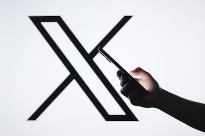 PARAGUAY - 2024/09/05: In this photo illustration, the X (Twitter) logo seen in the background with a silhouette hand holding a smartphone. (Photo Illustration by Jaque Silva/SOPA Images/LightRocket via Getty Images)