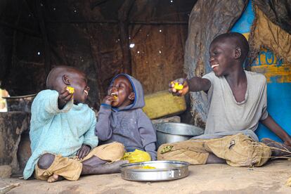 Los hermanos ugandeses Rahim, Emmanuel y lobuka (de izquierda a derecha) disfrutan de una comida en el campo de Bidi bidi, en el noroeste de Uganda, en 2022.