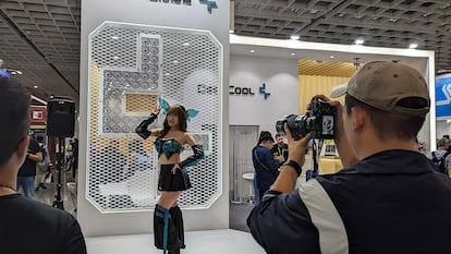 Un hombre le hace una foto a una chica en un stand de Computex.