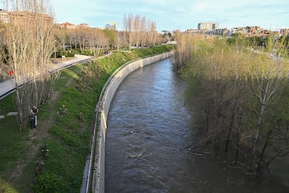 Varias personas junto al caudal del río Manzanares a su paso por Madrid Río, este miércoles.