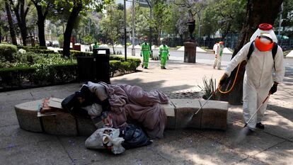 Agentes sanitários lavam praça no México, enquanto morador de rua dorme, em uma imagem de abril do ano passado.