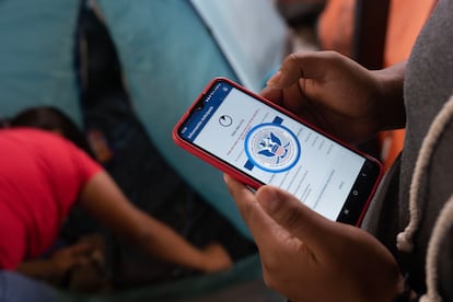 Una migrante mira en su teléfono móvil la aplicación CBP One en el albergue Juventud 2000, en Tijuana.
