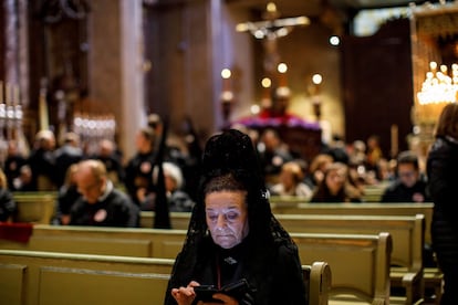Una mujer vestida de manola mira su teléfono móvil antes de iniciarse la procesión de Los Estudiantes en Madrid, el 25 de marzo.